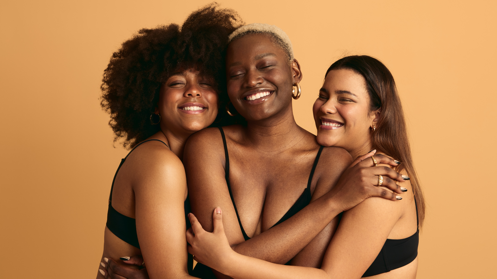 Three women embracing each other against a beige background